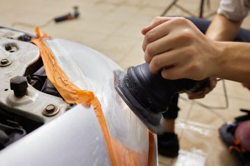 A man is spray painting a car in a garage.