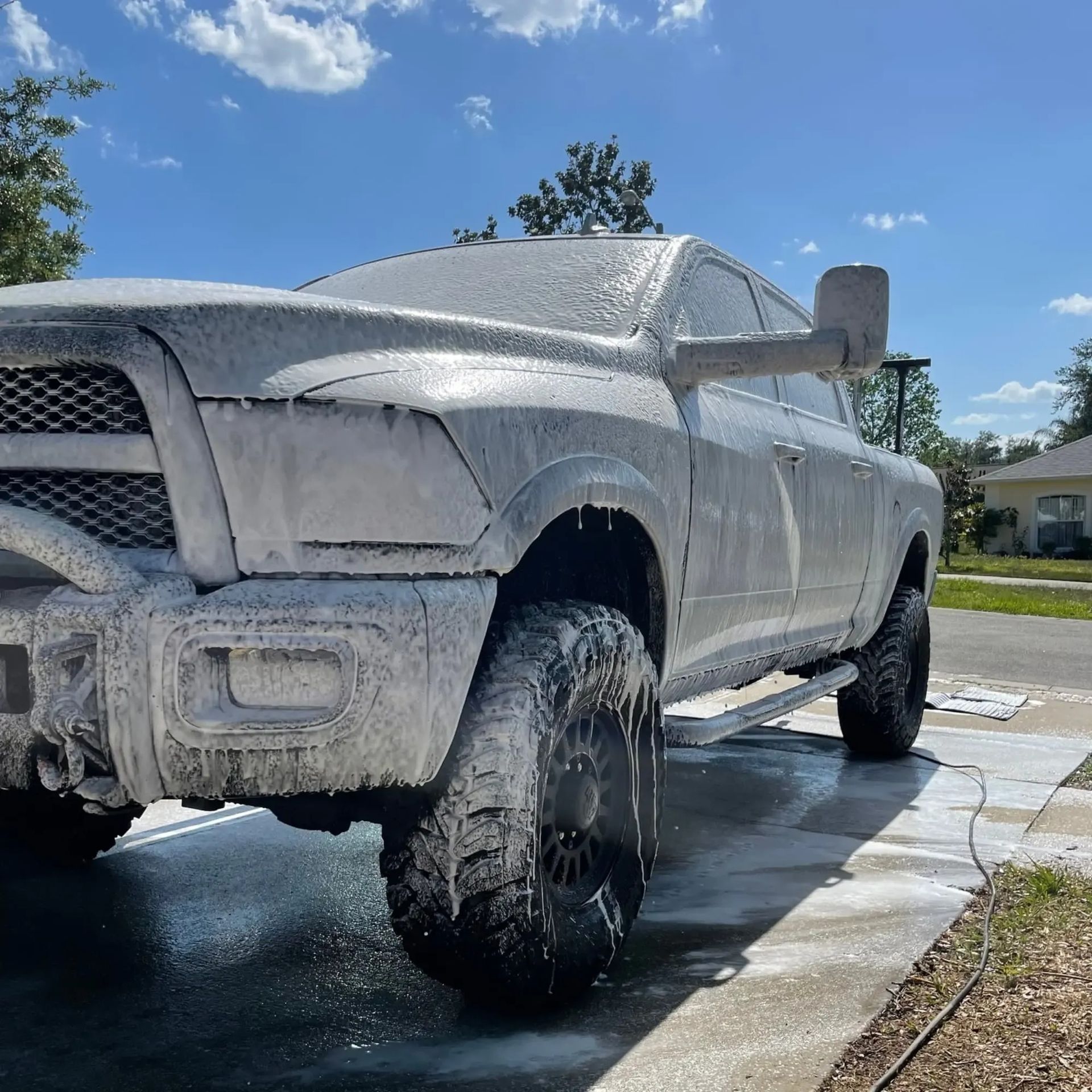 A white truck covered in foam is parked on the side of the road